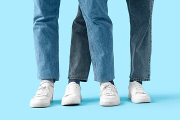 Young men in white sneakers on blue background