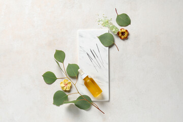 Acupuncture needles, sea salt, oil and eucalyptus leaves on light background