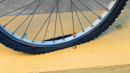 A bicycle tire lies flat against a yellow curb on a sunny afternoon, highlighting the need for...