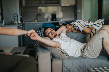 Obraz premium A group of friends enjoying a relaxed afternoon in a modern living room, showcasing friendship and leisure. One person reclines on the sofa while interacting with a friend.