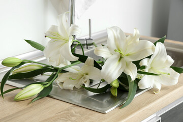 Bouquet of beautiful white lily flowers on sink in kitchen at home