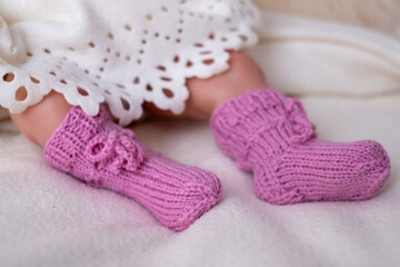 Soft pink knitted baby booties worn by an infant on a cozy blanket during a sunny afternoon at home