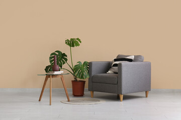 Armchair, houseplant and coffee table near beige wall in room