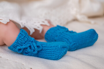 Bright blue knitted baby booties on a soft white blanket with delicate lace trim during a cozy indoor moment