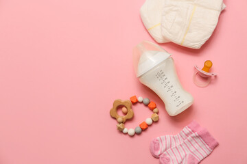 Bottle with milk for baby and accessories on pink background