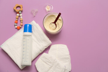 Feeding bottle with baby milk formula, diapers, pacifier and teether on lilac background