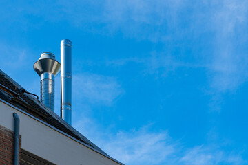 Metal exhaust stacks against a clear blue sky at midday
