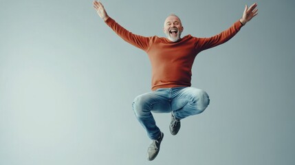Joyful middle-aged man jumping with arms raised in excitement on a grey background