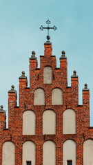 Gothic stepped gable facade of historic brick church with decorative cross
