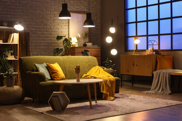 Sofa, coffee table with wooden hand and glowing lamps in interior of living room