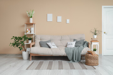 Sofa, decorated tree, shelving unit and pouf with book in interior of living room