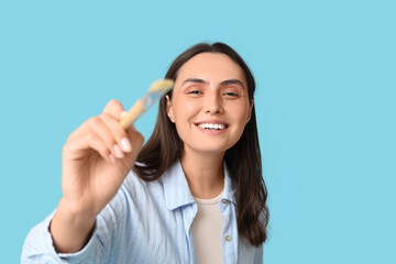 Beautiful female artist with brush on blue background