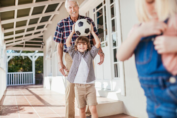 Grandfather and son bonding while playing with a soccer ball on house porch