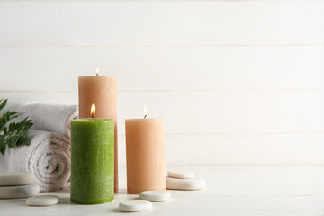 Candles, spa stones and towels on light background