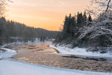 Gauja river on frosty and snowy winter evening during the sunset in Sigulda, Latvia