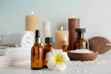 Essential oil, flower, candles and spa supplies on light background