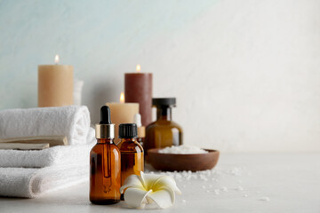 Essential oil, flower, candles and spa supplies on light background