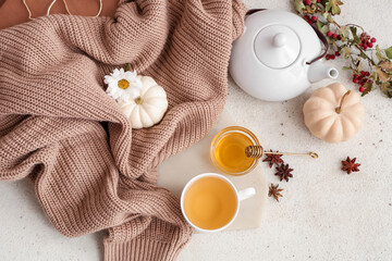 Composition with tray, cup of green tea, tea pot and sweater on light grunge background