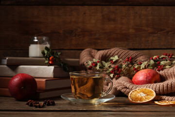Composition with cup of green tea, apples and sweater on wooden table near wall