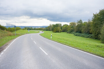 The road leading to the city goes into the distance. A lonely red car on the road. A winding road...