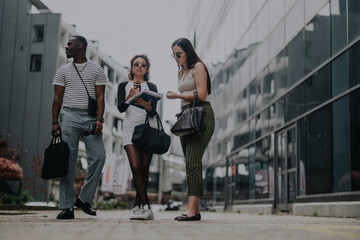 Obraz premium Three business people are engaged in a discussion outside in a modern urban setting, highlighting teamwork, communication, and contemporary style.