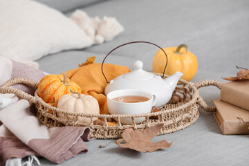 Teapot and cup of tea with autumn decor on tray in living room