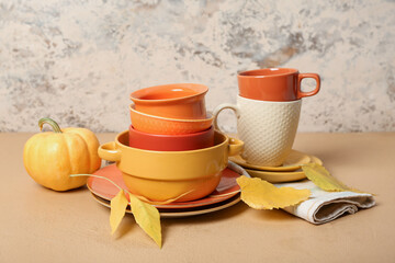 Stack of dishes with autumn decor and pumpkins on table against grunge background
