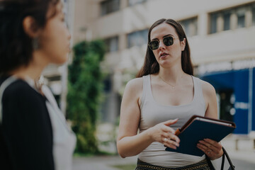 Multicultural business team engaging in an outdoor meeting, exchanging ideas and strategies for future projects. Professionals discuss revenue growth and project analysis in a vibrant city setting.