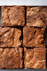 Delicious baked chocolate brownies cut into squares, ready to serve, placed on a white surface with subtle textures visible