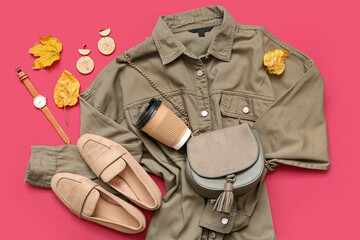 Stylish female bag with shirt, shoes, accessories and autumn leaves on red background