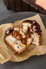 Heart-shaped baked good with chocolate and caramel filling served on parchment paper at a café