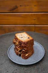 A delicious homemade banana bread loaf sits on a rustic plate against a wooden backdrop