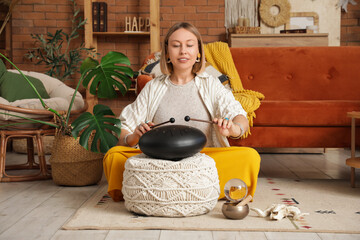 Beautiful woman with sticks playing glucophone on carpet at home