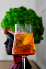 A refreshing cocktail served in a stylish glass with a vibrant green decorative piece in the background