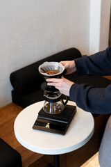 Brewing coffee with a pour-over dripper on a wooden table in a cozy café setting during the afternoon