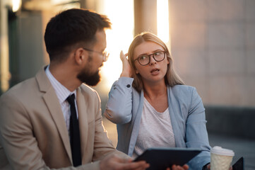 Businesspeople having disagreement while reading bad news on tablet during outdoor meeting