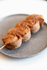 Deliciously twisted sweet treat served on a wooden stick, highlighting the golden-brown caramelization and unique presentation at a trendy café