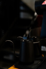 Black coffee pouring kettle and detailed workspace setup for brewing coffee during the early morning hours at a local café