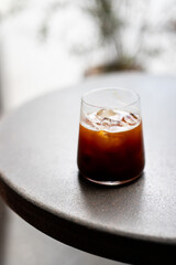 A refreshing glass of iced coffee rests on a round table in a cozy cafe during a sunny afternoon