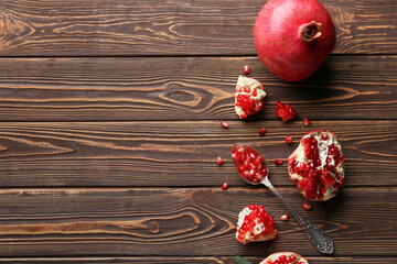 Fresh ripe pomegranates and spoon with seeds on wooden background