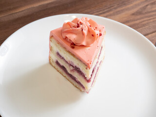 close-up of a piece of delicious layer cake on a white plate. Wooden table, dark background