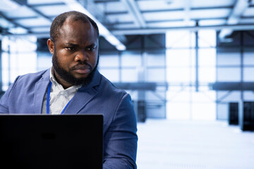 Engineer in data center using tools on laptop designed to handle challenges of managing cloud and...