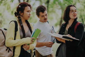 A diverse group of students working together on assignments outdoors, fostering teamwork and collaboration. They are engaged and focused, enjoying the fresh air and natural environment of the park.
