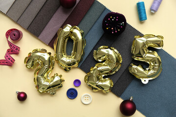 Figure 2025 with fabric samples, sewing supplies and Christmas balls on yellow background