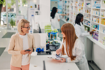 Female pharmacist helping senior woman choosing prescription drug