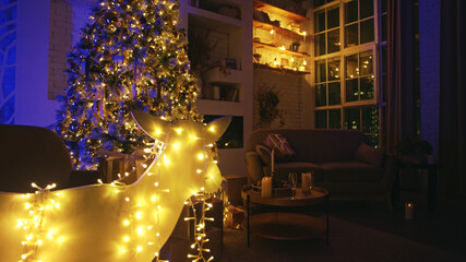 Cozy living room is glowing with warm christmas lights in the evening, creating a festive atmosphere. A luminous reindeer decoration adds a touch of whimsy to the scene