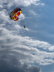 Silhouette of a man parasailing in a blue sky.