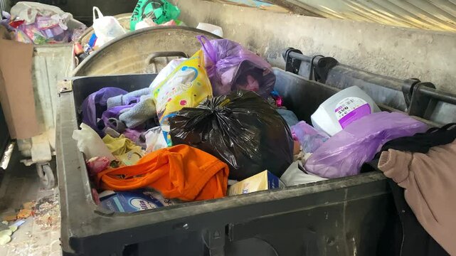 A garbage container filled with various household waste. Garbage can