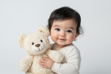 Smiling baby hugging a plush teddy bear against a white background