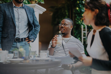 Mixed race business professionals brainstorming and strategizing in a modern coffee bar, sharing ideas and collaborating effectively.